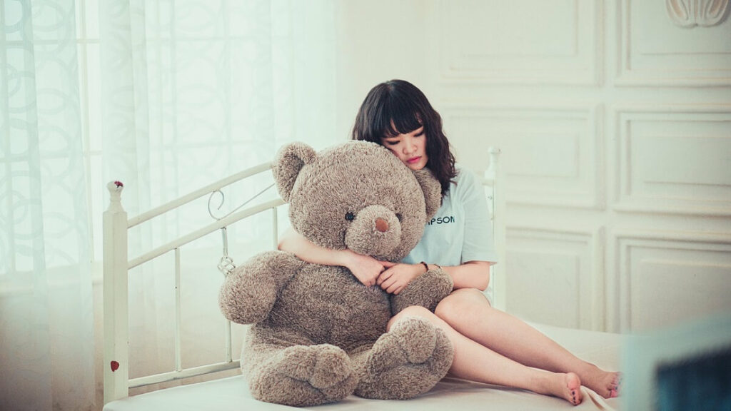 Jovem com urso na cama em Quarto juvenil