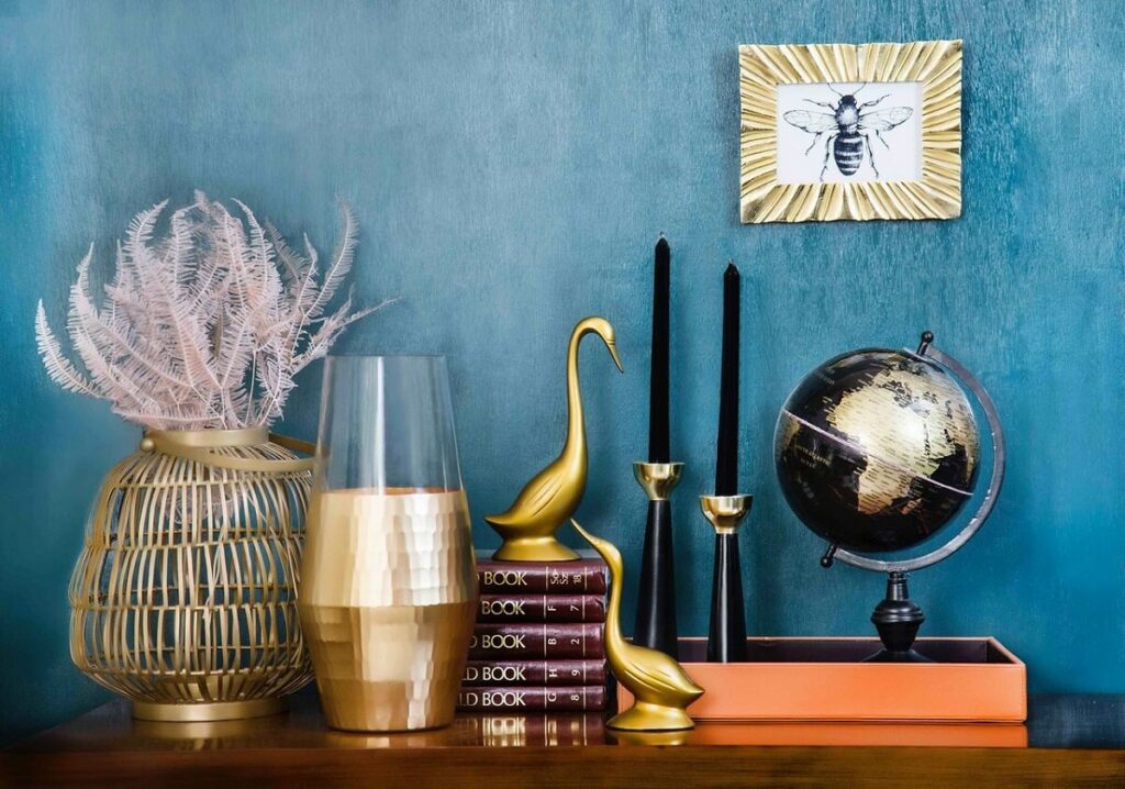 Objetos afetivos na decoração de casa 1 Quadro na parede e objetos decorativos sobre o móvel em uma parede azul no fundo