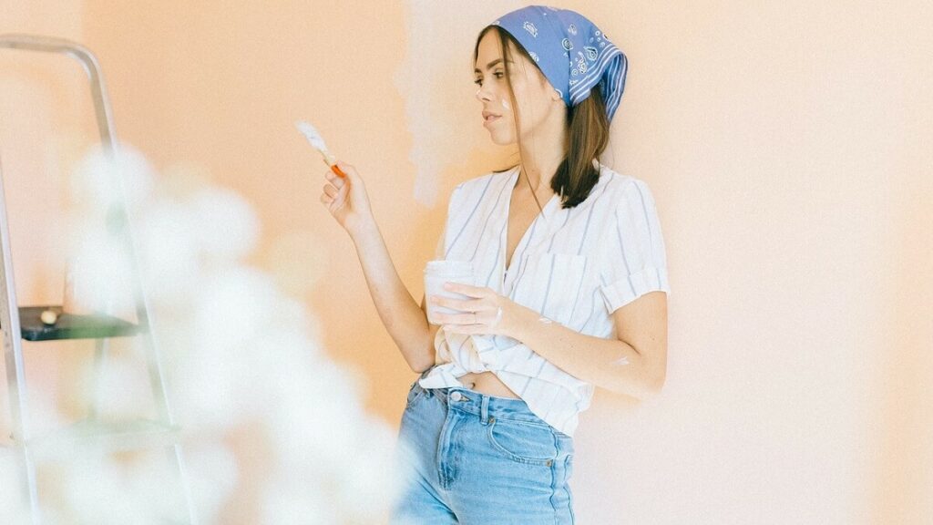 Mulher pintando seu quarto, para renovar a decoração
