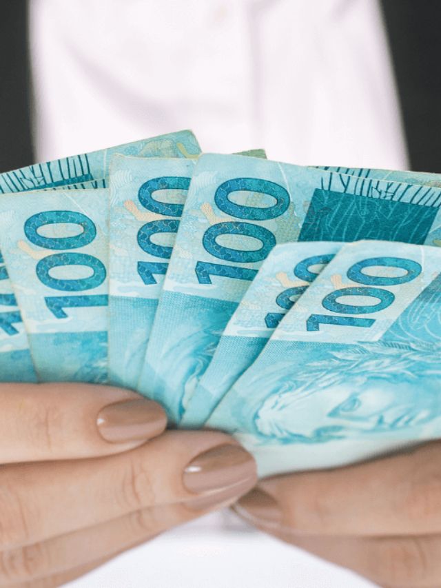 Mulher segurando cédulas de 100 reais