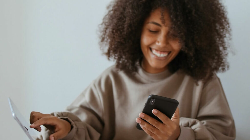 Mulher rindo com celular na mão