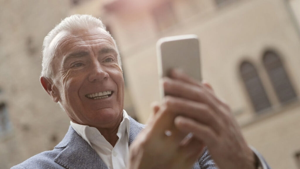 O que significa kkkk no WhatsApp: Confira mais aqui! 4 Homem rindo e olhando para celular