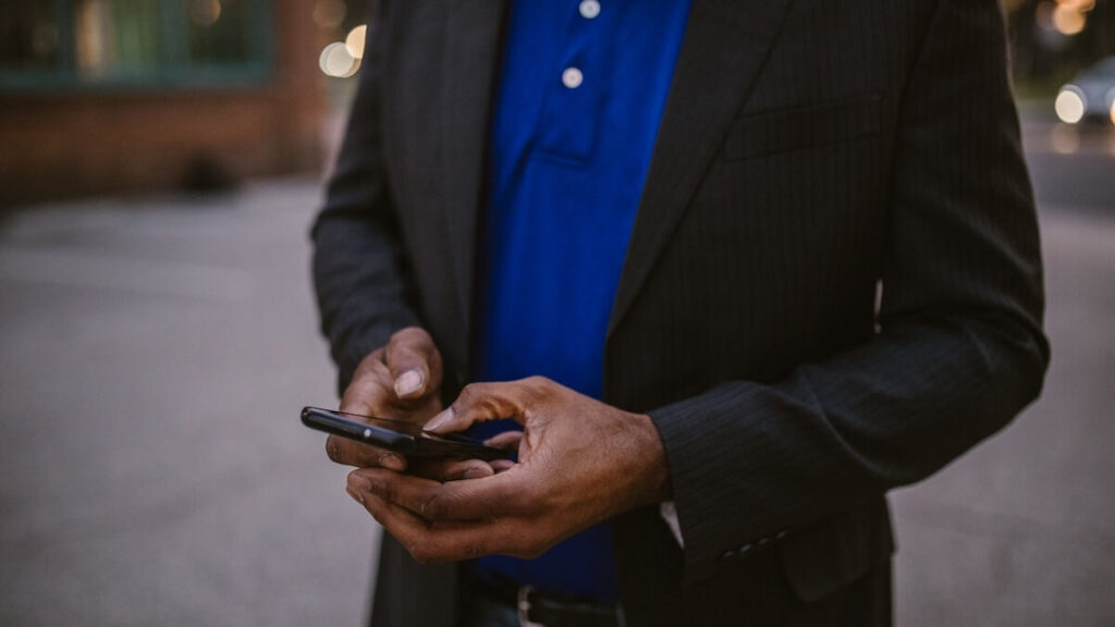 O que significa vdd no WhatsApp: Veja já! 2 Homem de terno e camisa azul escura, mexendo em seu celular