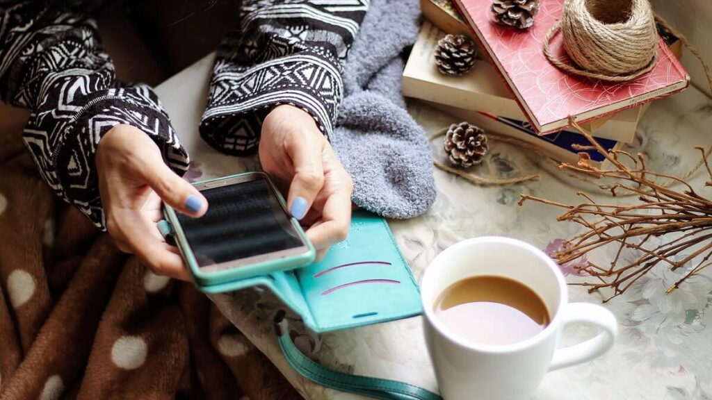 O que significa dlc no WhatsApp? Veja como usar essa abreviação corretamente! 2 Pessoa usando o celular e tomando café