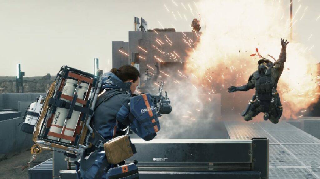 Imagem do jogo mostrando um personagem segurando uma arma pesada e o outro voando após uma explosão.