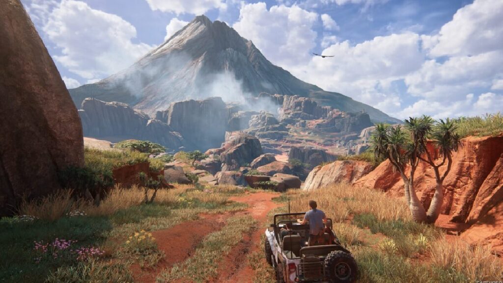 Imagem do jogo mostrando um personagem em cima do jipe em uma vegetação seca e cheia de montanhas.