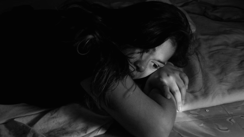 Mulher triste deitada em uma cama no escuro.