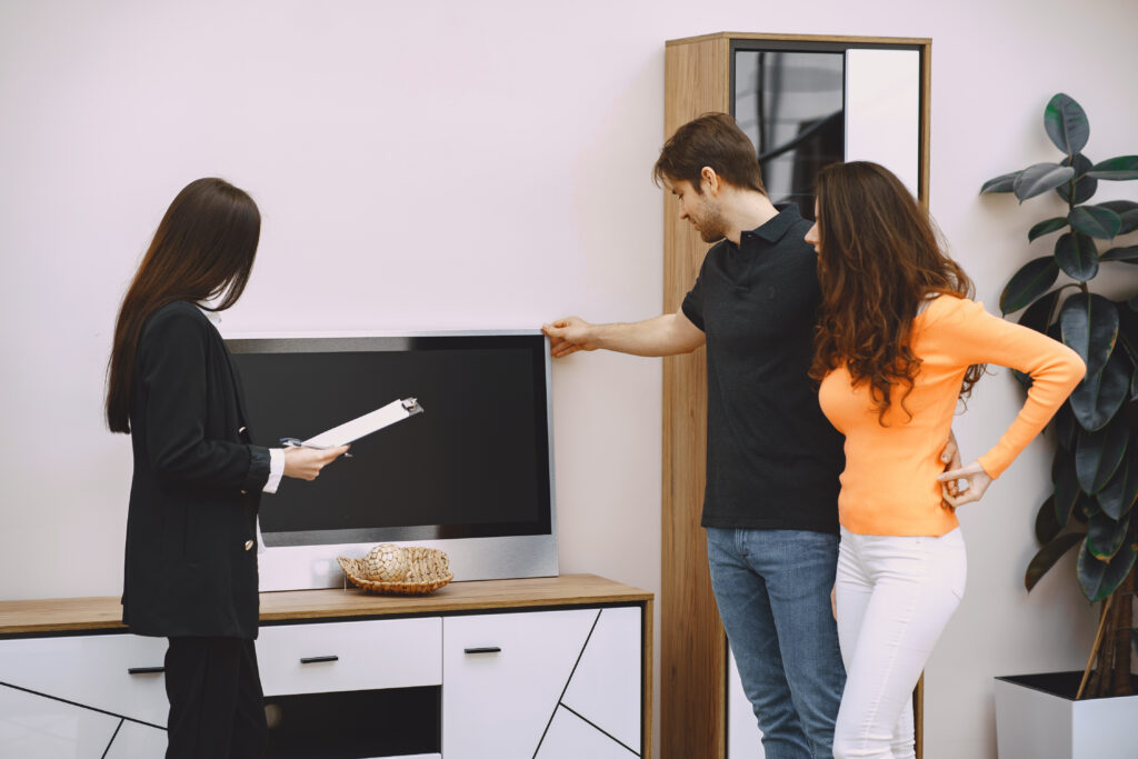 Guia prático: como avaliar o tamanho da televisão antes da compra? 1 Casal olhando o tamanho da televisão antes de comprar.